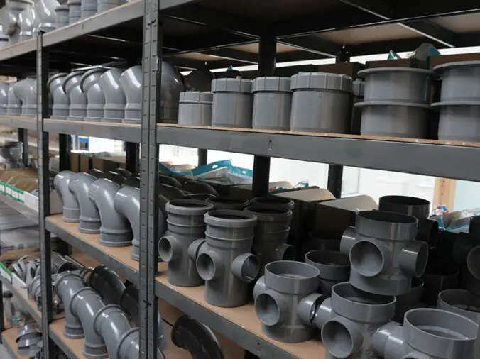 Large grey PVC elbows and connectors in a plumbing supply warehouse