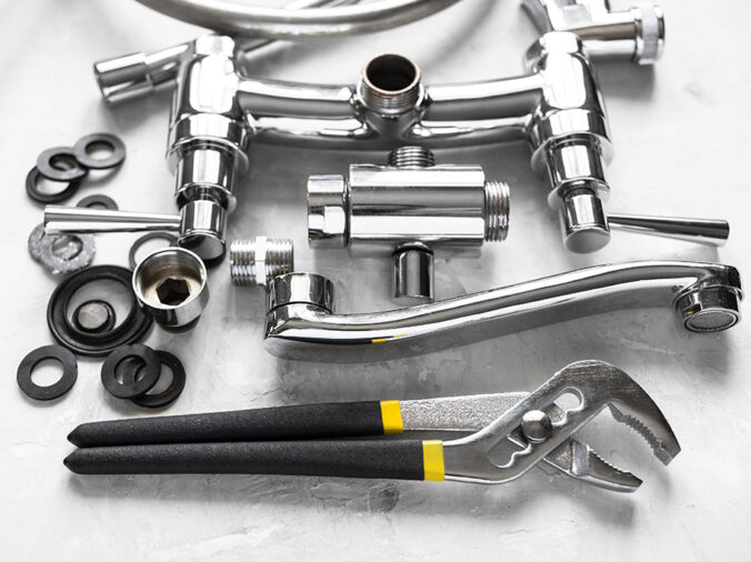 Disassembled chrome sink faucet and plumbing wrench